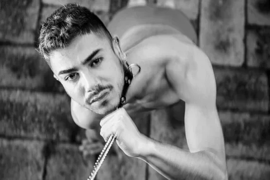 Svart-hvitt kunsttrykk av COMPELLED - DAMIAN av Arjan Spannenburg, med en mann med krage og lenke.