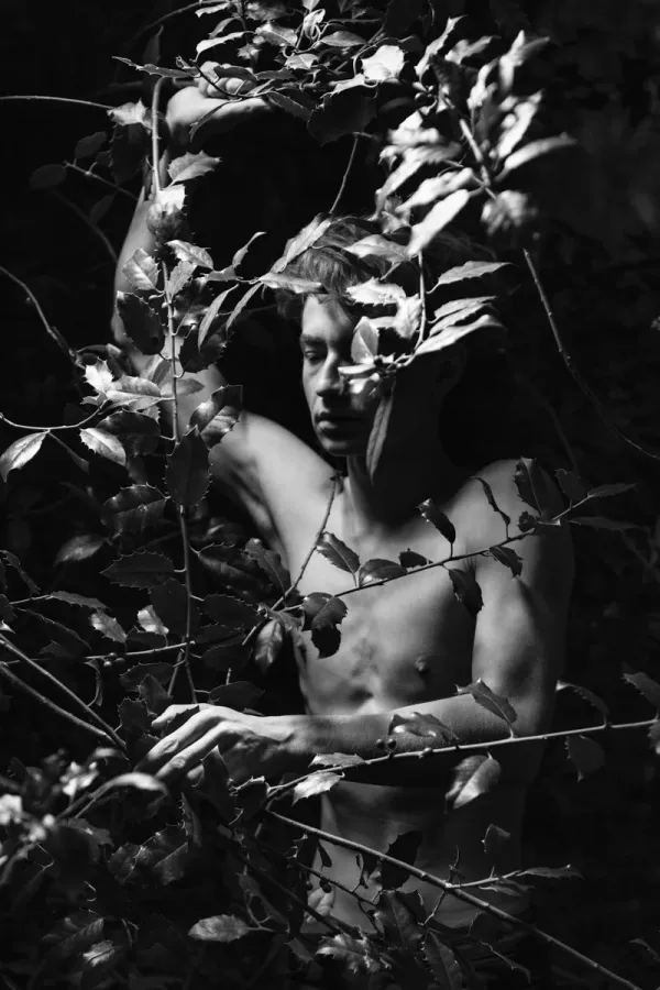 A black and white conceptual fine art portrait of RICARDO for the ESTRANGED series by ARJAN SPANNENBURG, featuring a man among prickly holly leaves.