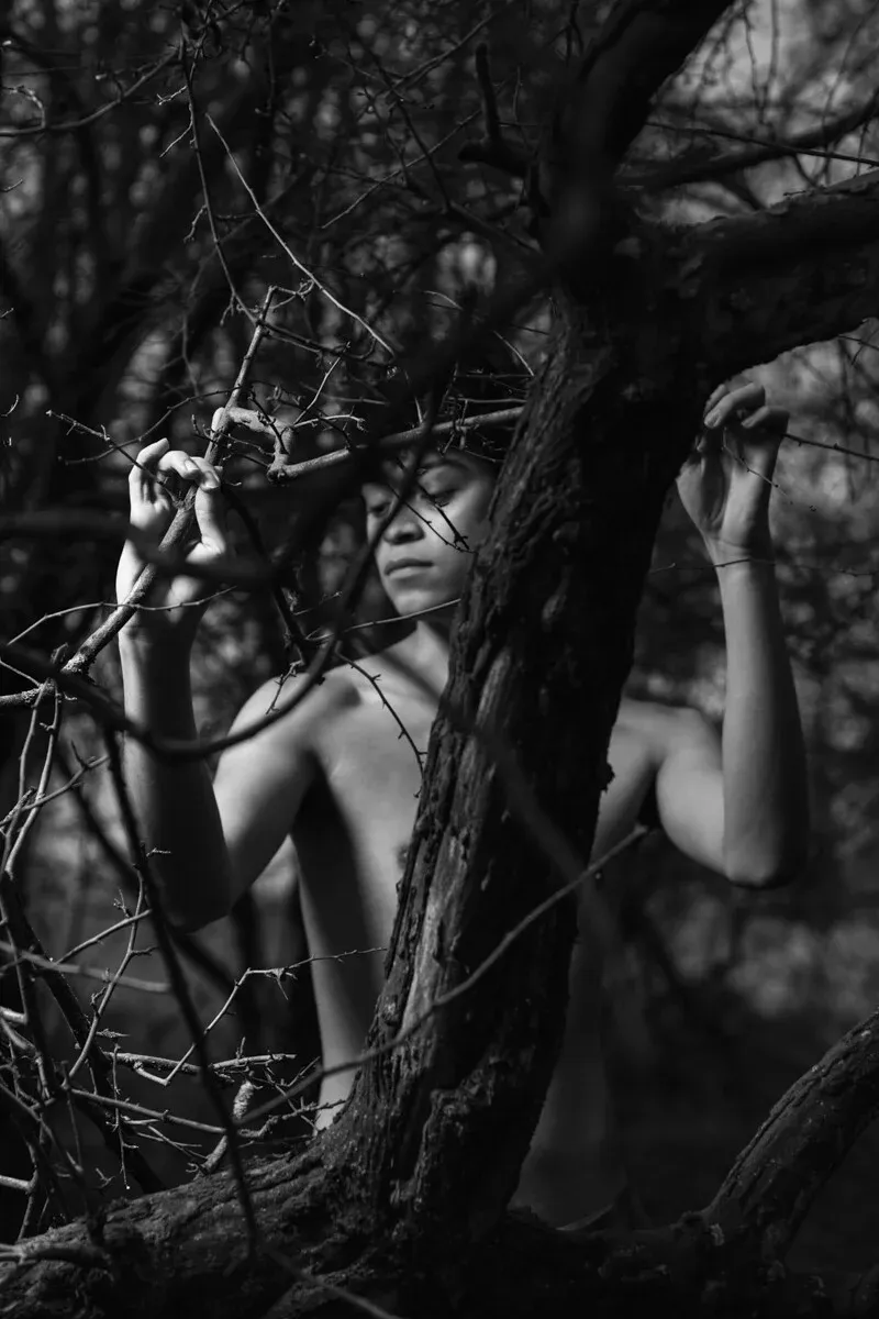 A black and white conceptual fine art portrait of WILSON for the ESTRANGED series by ARJAN SPANNENBURG, showing a man behind a thick tree trunk.