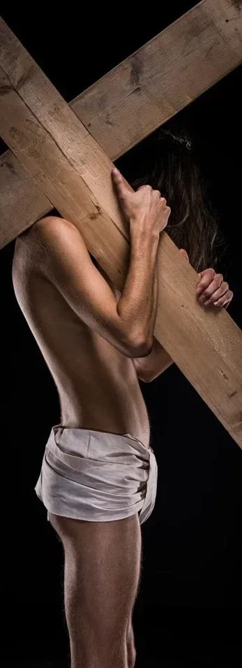 Contemporary fine art photograph by Arjan Spannenburg titled IMPERISHABLE, featuring a side profile of a male subject carrying a large wooden cross against a black background in a Dutch Master chiaroscuro style.